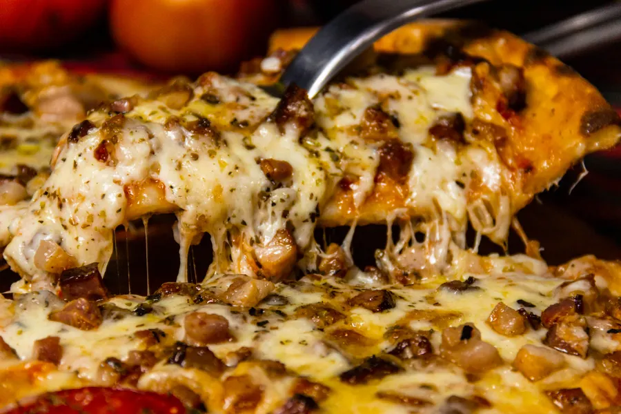 Frische Pizza mit goldbraunem Käse und einem herausgehobenen Stück